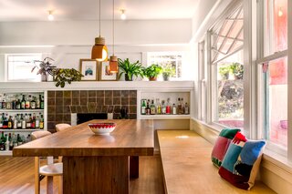 A built-in bench provides seating for the 10-foot-long dining table, which Lanigan found at a store in Berkley that was going out of business. “It almost feels like it grows out of the floor,” says Lanigan. (The fireplace tile here is original.)