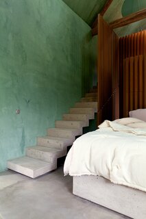 A concrete staircase leads to a newly added mezzanine that contains Onur and Alix’s bathroom and a small sauna.  A gloss-sealed MDF closet doubles as a headboard for the couple’s floating concrete bed. Behind the closet is the girls’ bedroom and bath.