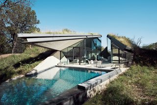 Edgeland House, built on a cliff-top lot in Austin by architect Thomas Bercy for lawyer and writer Chris Brown, is topped by a living roof to help it blend into the landscape. The concrete, steel, and glass house is divided into two distinct public and private halves. <span style="font-family: Theinhardt, -apple-system, BlinkMacSystemFont, &quot;Segoe UI&quot;, Roboto, Oxygen-Sans, Ubuntu, Cantarell, &quot;Helvetica Neue&quot;, sans-serif;">Tucked beneath a grassy roof covered by nearly 200 species of plants and grasses, the structure is virtually invisible from the nearby street. In fact, the 1,400-square-foot house is so well hidden in the earth that it doesn’t seem to register on the radar of local wildlife either.  Birds, butterflies, bees, dragonflies, hawks, snakes, lizards, and frogs all treat the house like just another grassy knoll.</span>