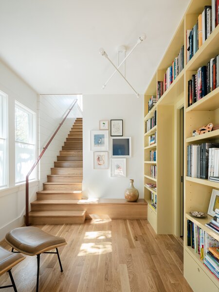 The gallery includes a built-in bookcase painted in Farrow &amp; Ball’s Hay, which complements the white oak flooring. A sculptural light, chosen in white to match the ceiling and walls, adds visual interests.