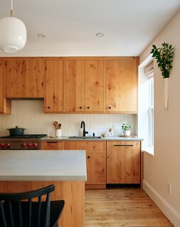 The homeowners chose knotty alder cabinets and concrete countertops, starkly contrasting with the rest of the home. A white tile backsplash draws attention to the black faucet and barstools.