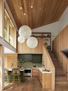 The kitchen underwent the most dramatic change, being relocated to the back of the house adjacent to the living room. White Oak floors and casework and new Kolbe windows warm up the space. The pendant light is from Design Within Reach, and the bar stools are custom from Sean Woolsey.