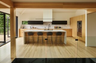 The renovated kitchen is open, airy, and connected to the rest of the main level. Plum Projects used Bedrosians Magnifica Luxe polished white porcelain for the island, countertops, and backsplash. The black upper cabinets are made from Richlite: a durable, sustainable material made from recycled paper.