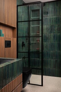 There’s more concealed storage in the bathroom, this time clad in wooden tile so it blends in with the wall treatment. The flooring is terrazzo tile.