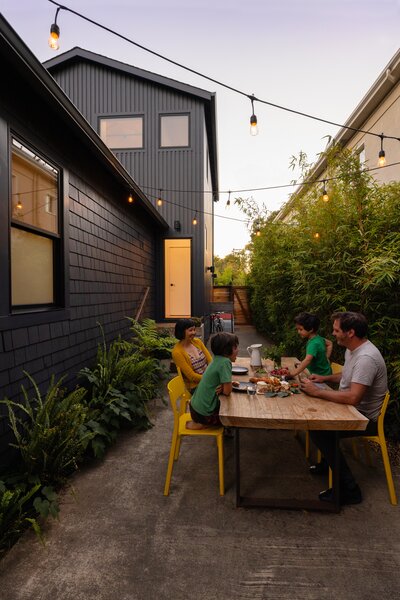 What used to be the driveway is now a private side patio where the family regularly eats dinner. Ikea chairs join a table the couple made themselves.